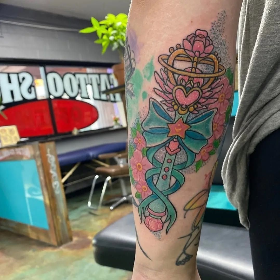 A woman has a tattoo of a bow and flowers on her forearm