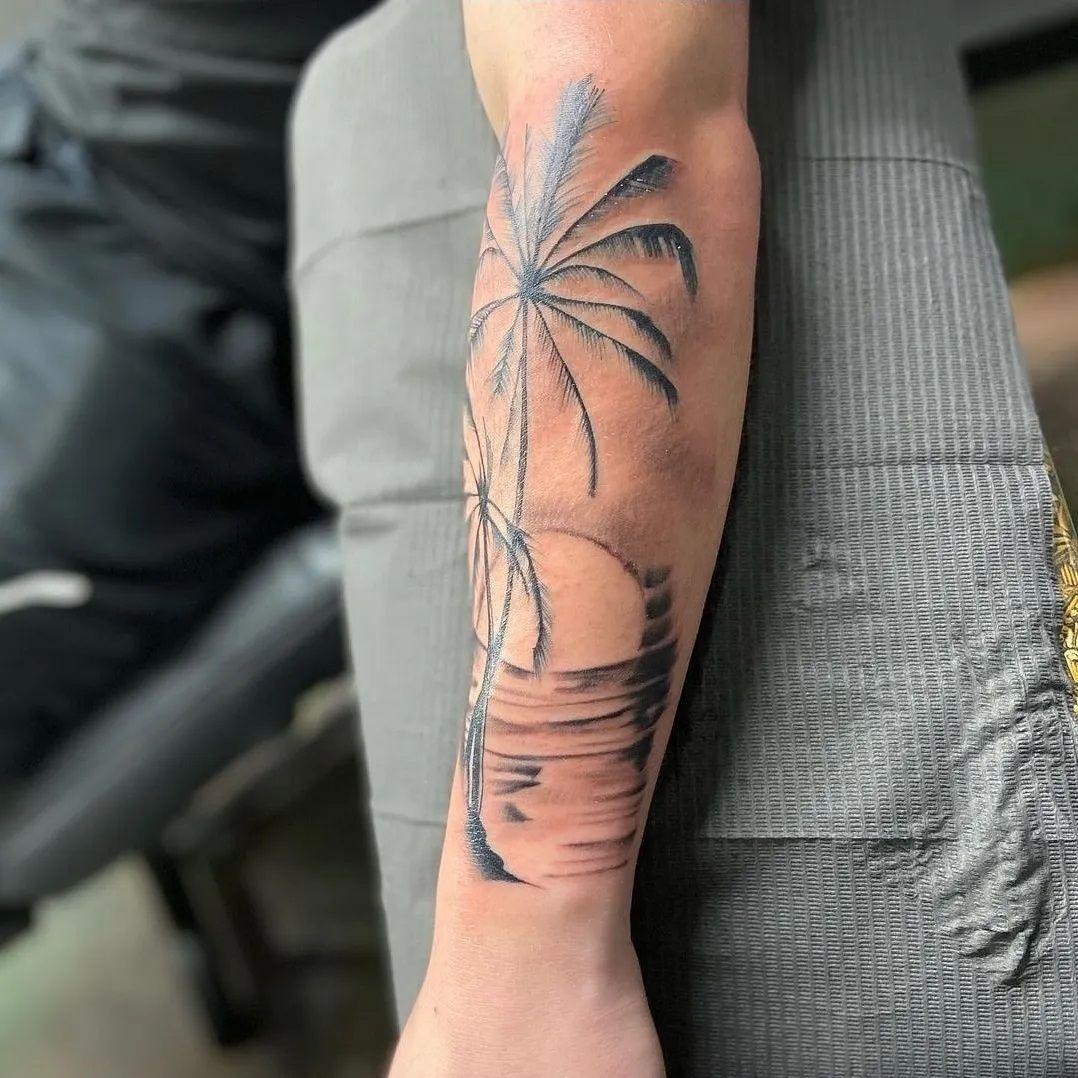 A man has a tattoo of a palm tree on his forearm.