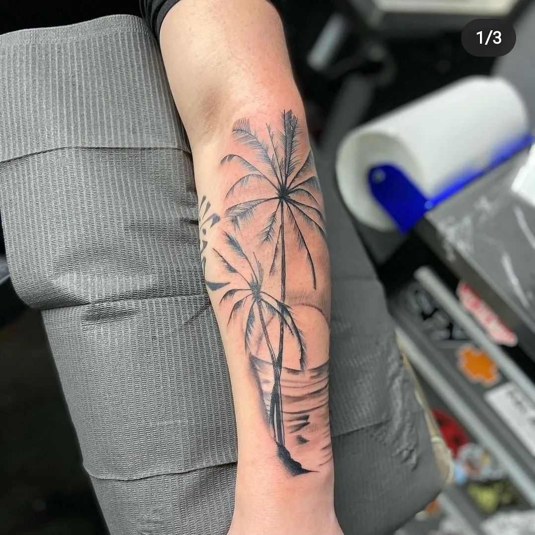 A person has a tattoo of palm trees on their forearm