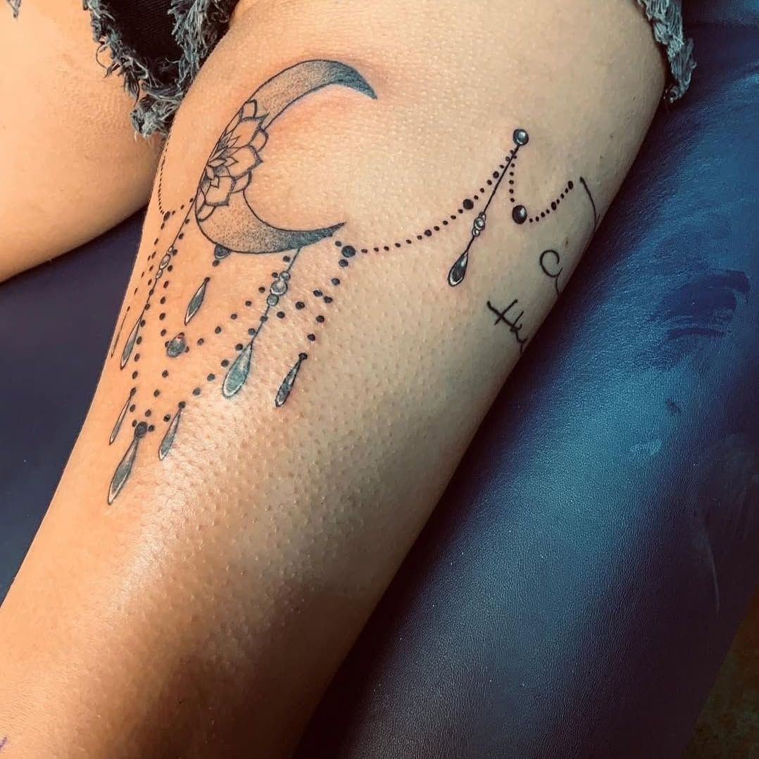 A woman has a tattoo of a crescent moon on her leg