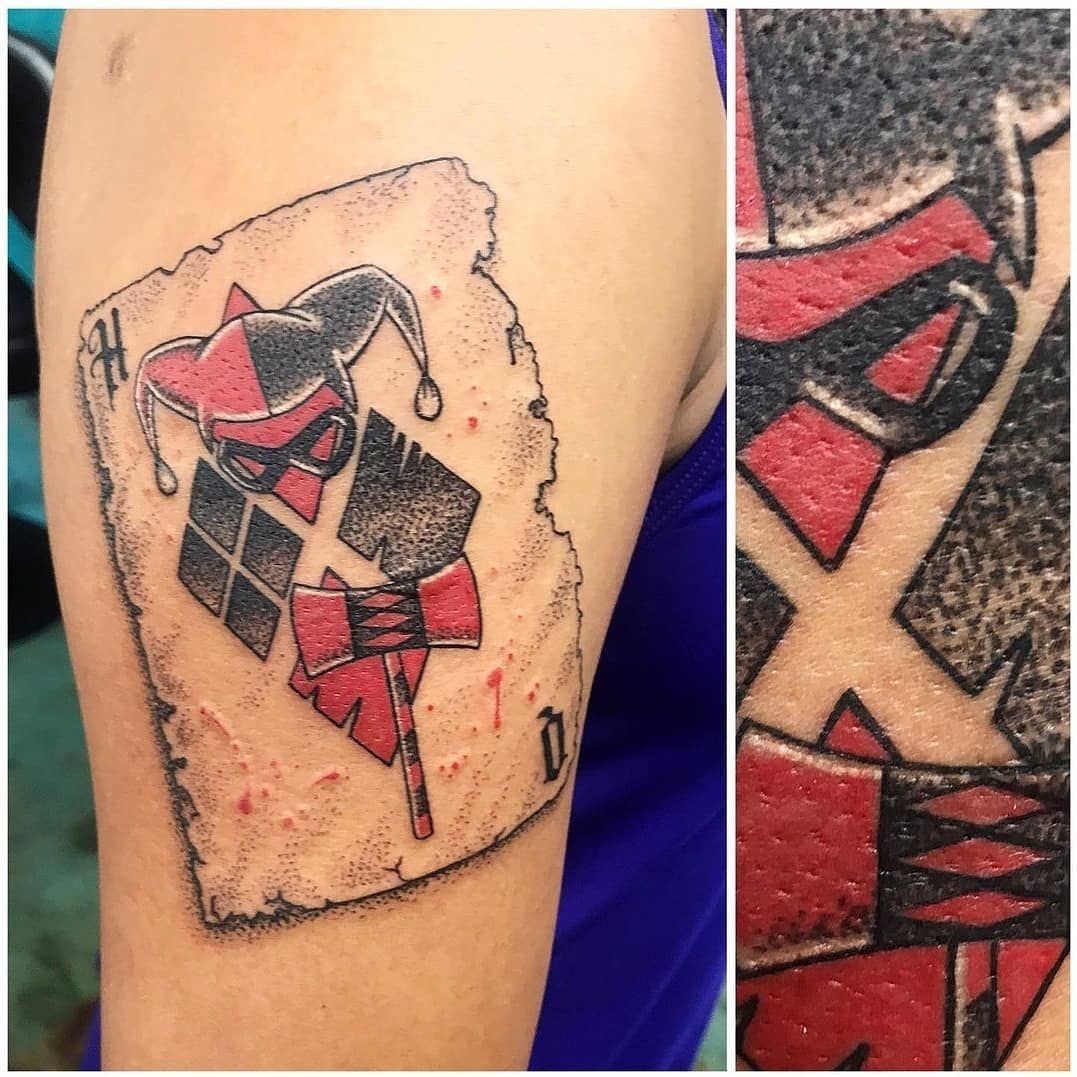 A tattoo of a harley quinn playing card on a person 's arm