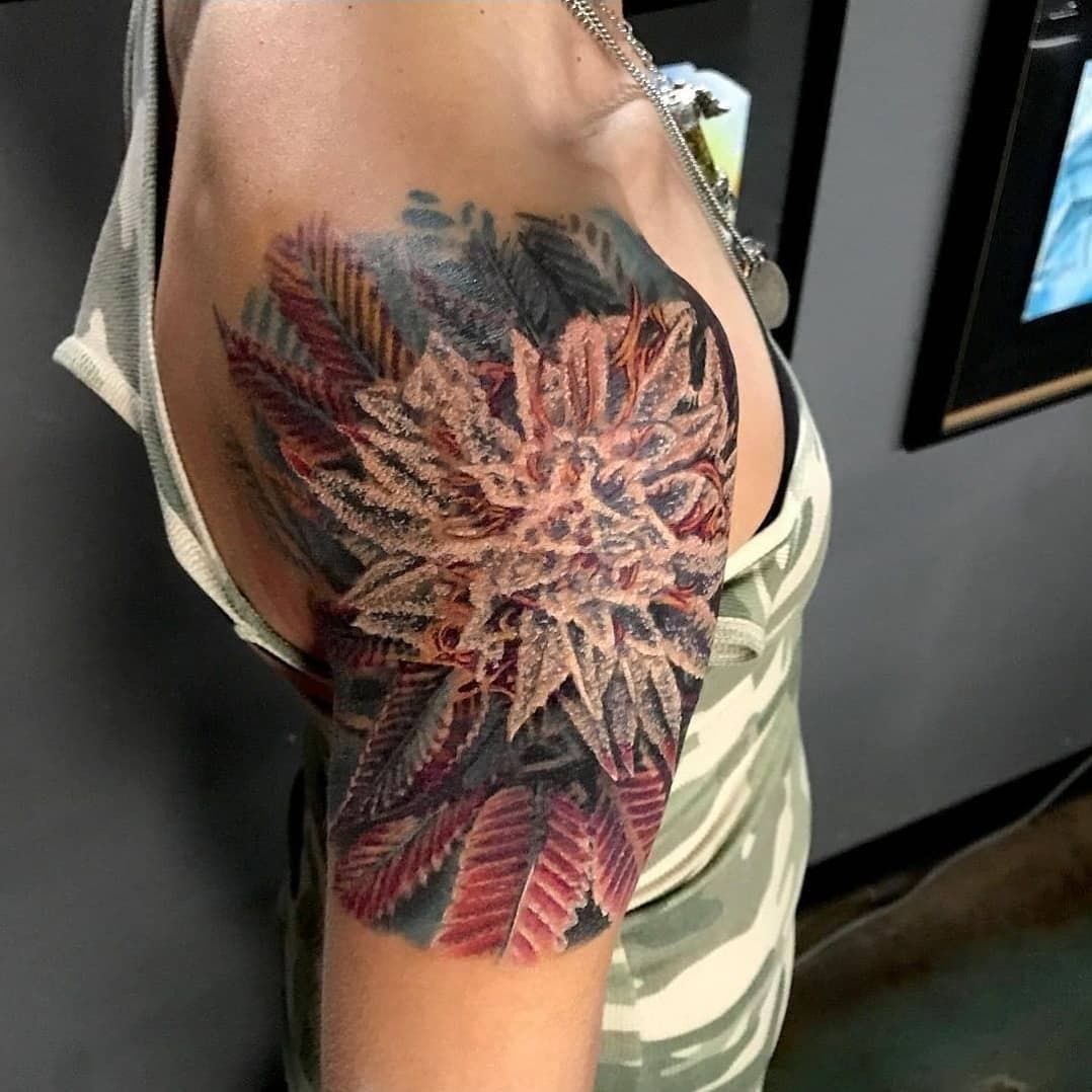 A woman has a tattoo of a flower on her shoulder
