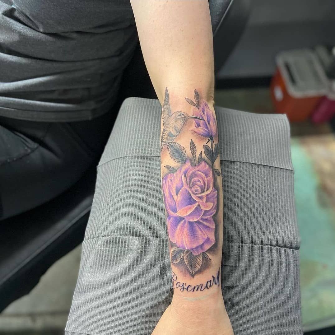 A woman has a tattoo of purple roses on her forearm