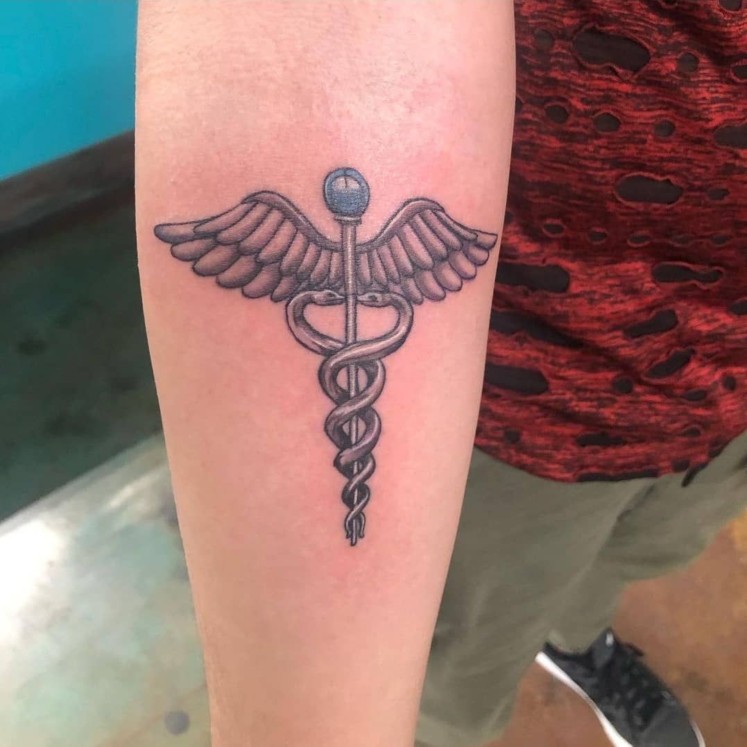 A person has a caduceus tattoo on their forearm
