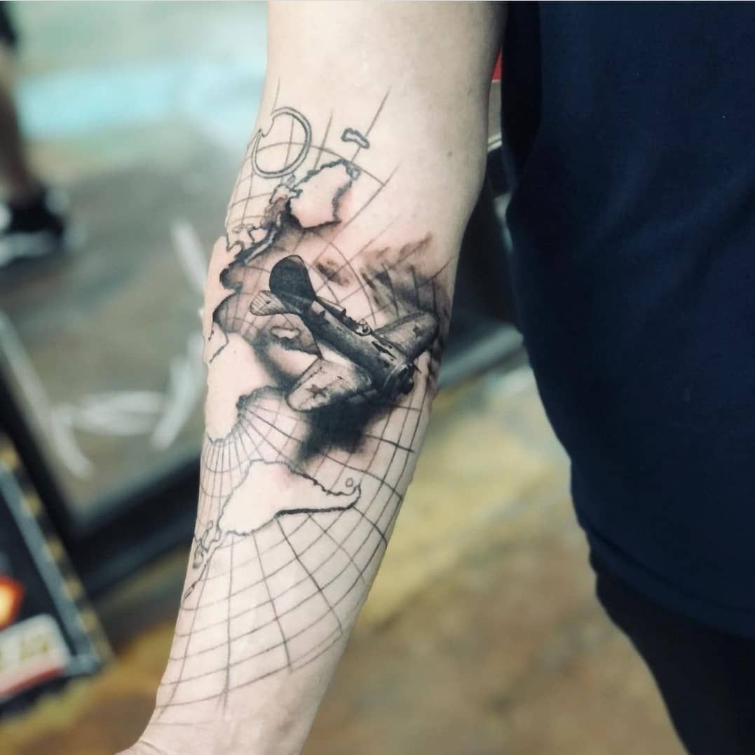 A person has a tattoo of a globe on their forearm