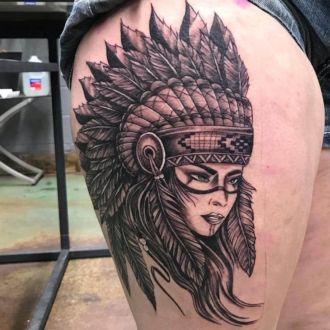 A black and white tattoo of a woman wearing a native american headdress.