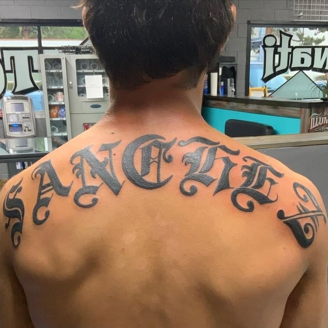 A man has a tattoo on his back that says sangita