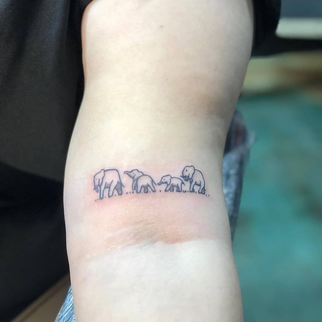 A tattoo of a family of elephants on a person 's arm