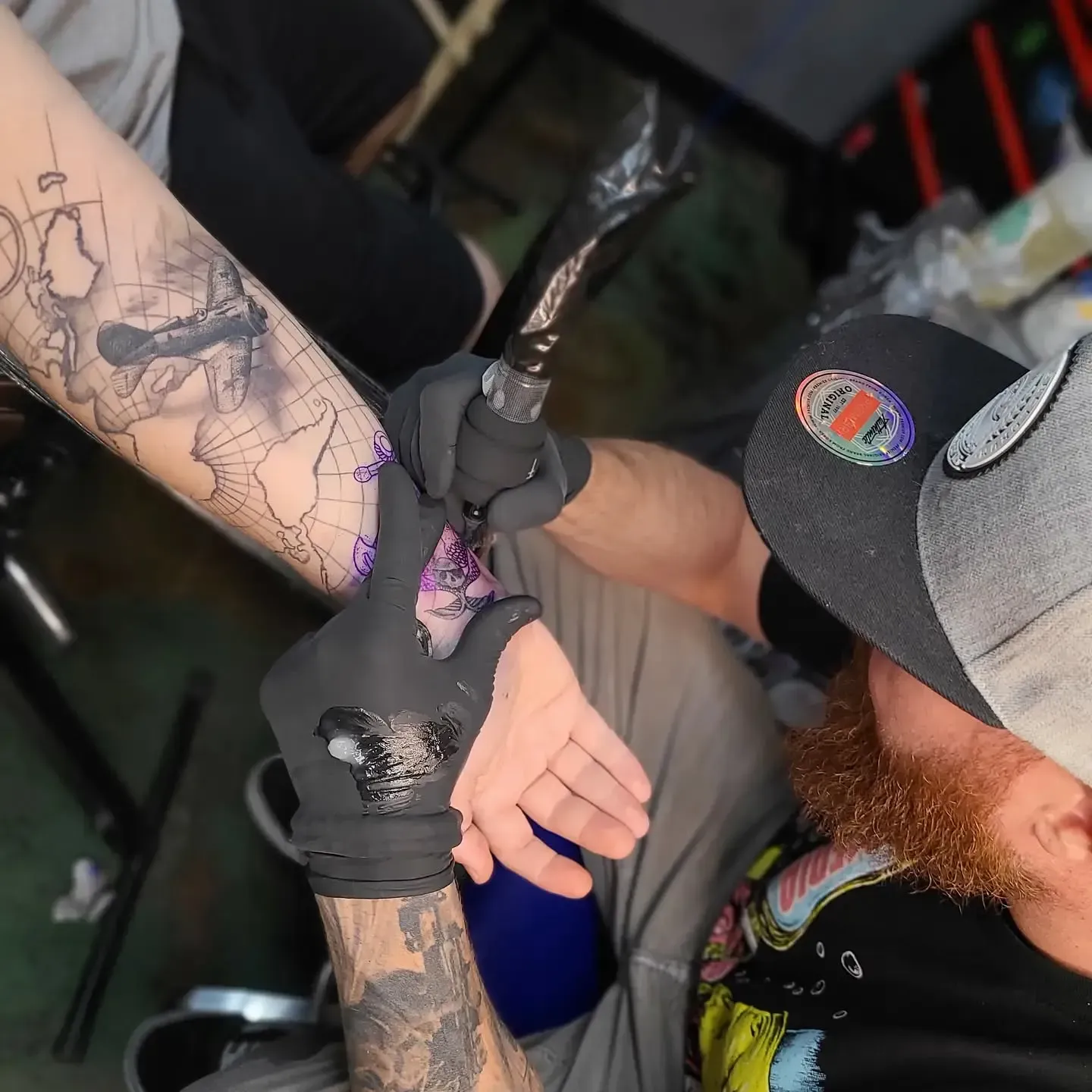 A man with a beard is getting a tattoo on his arm