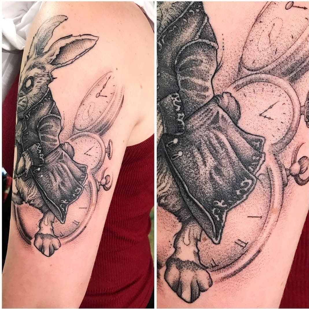 A woman has a tattoo of a rabbit and a clock on her arm.