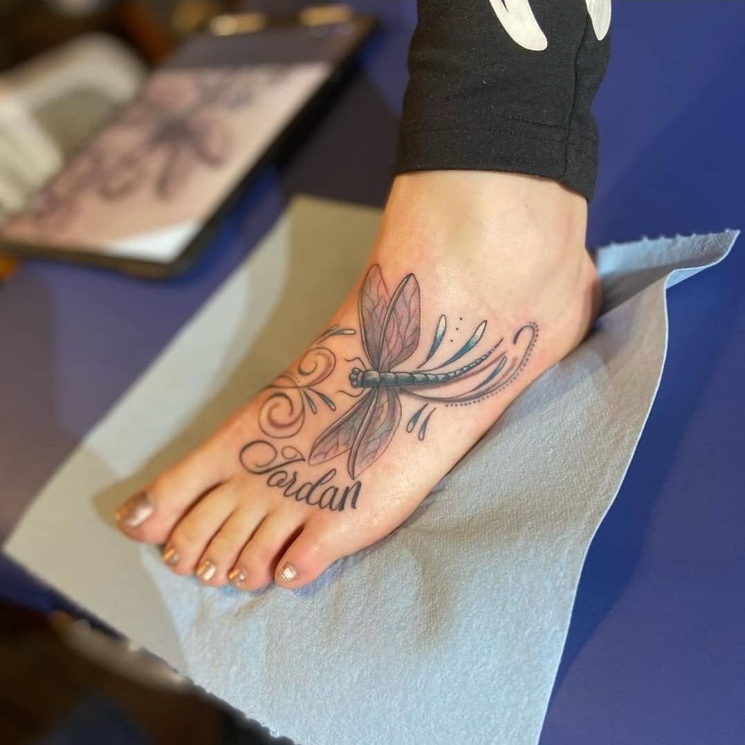 A foot with a dragonfly tattoo and the name jordan