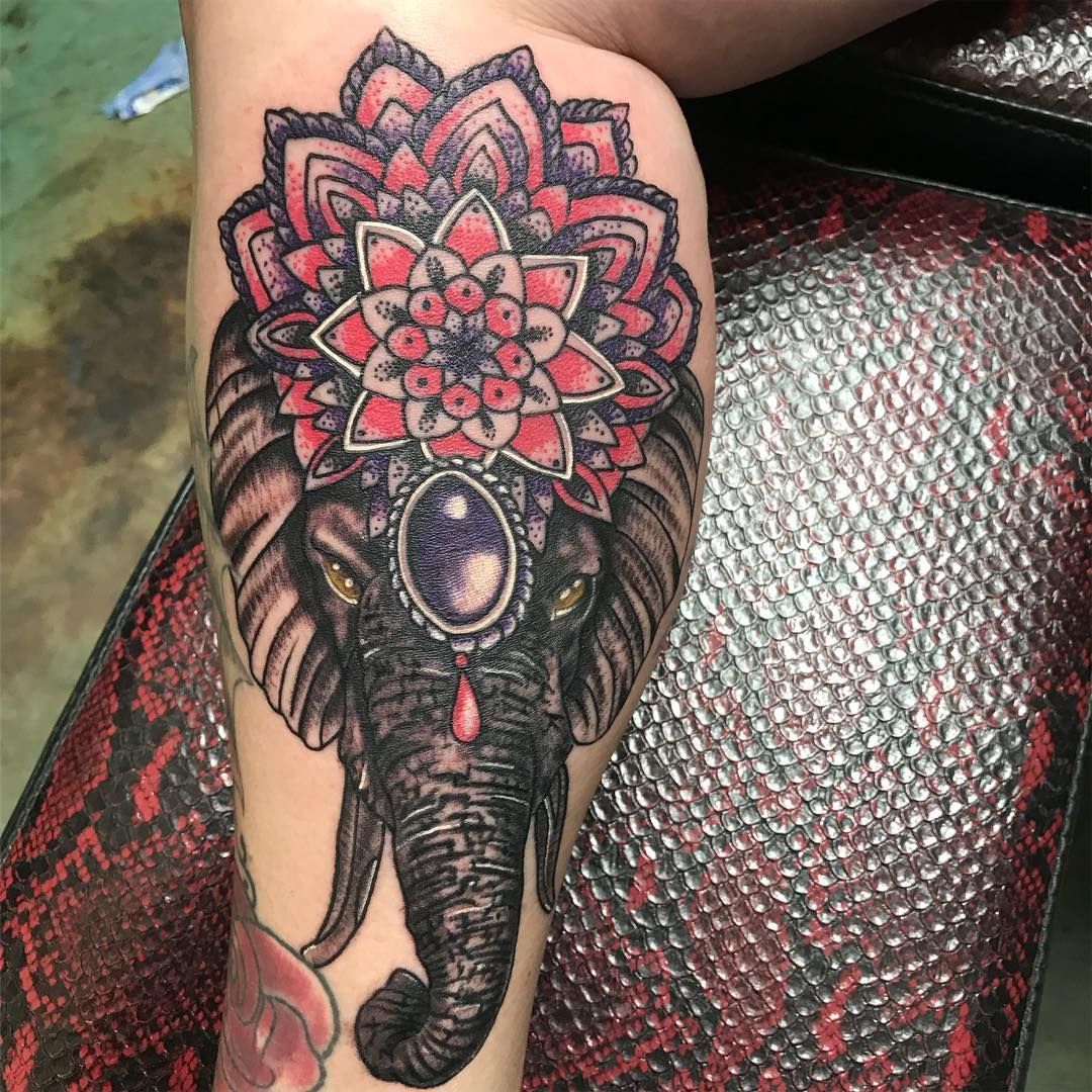 A person has a tattoo of an elephant with a mandala on their leg.