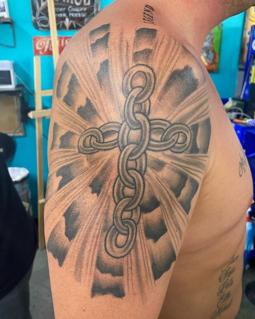 A man has a tattoo of a cross on his arm