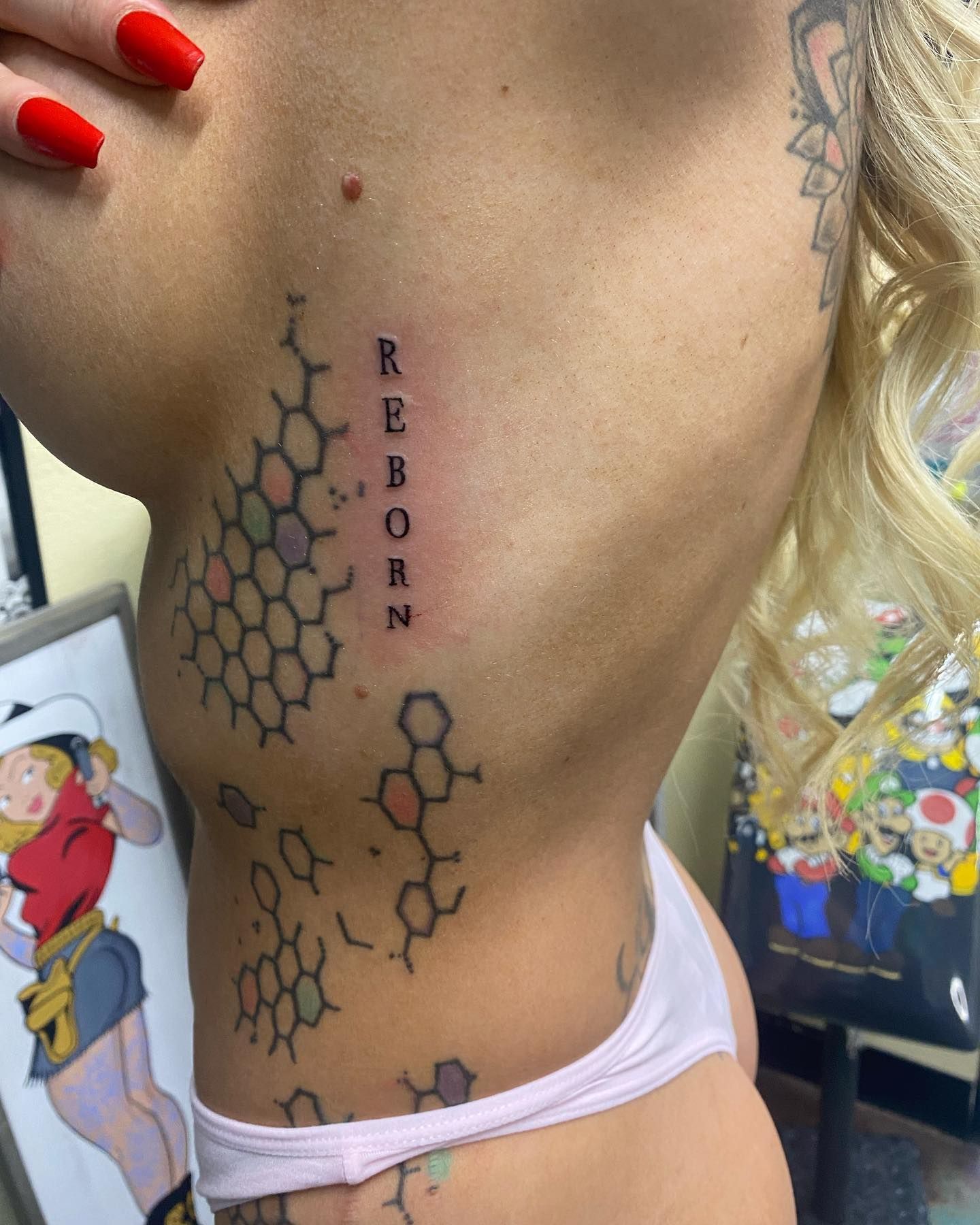 A woman has a tattoo on her side that says reborn