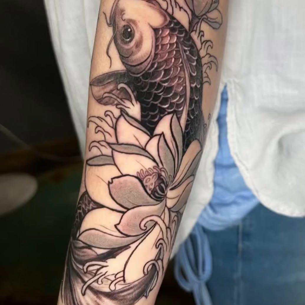 A woman has a tattoo of a fish and flowers on her arm.