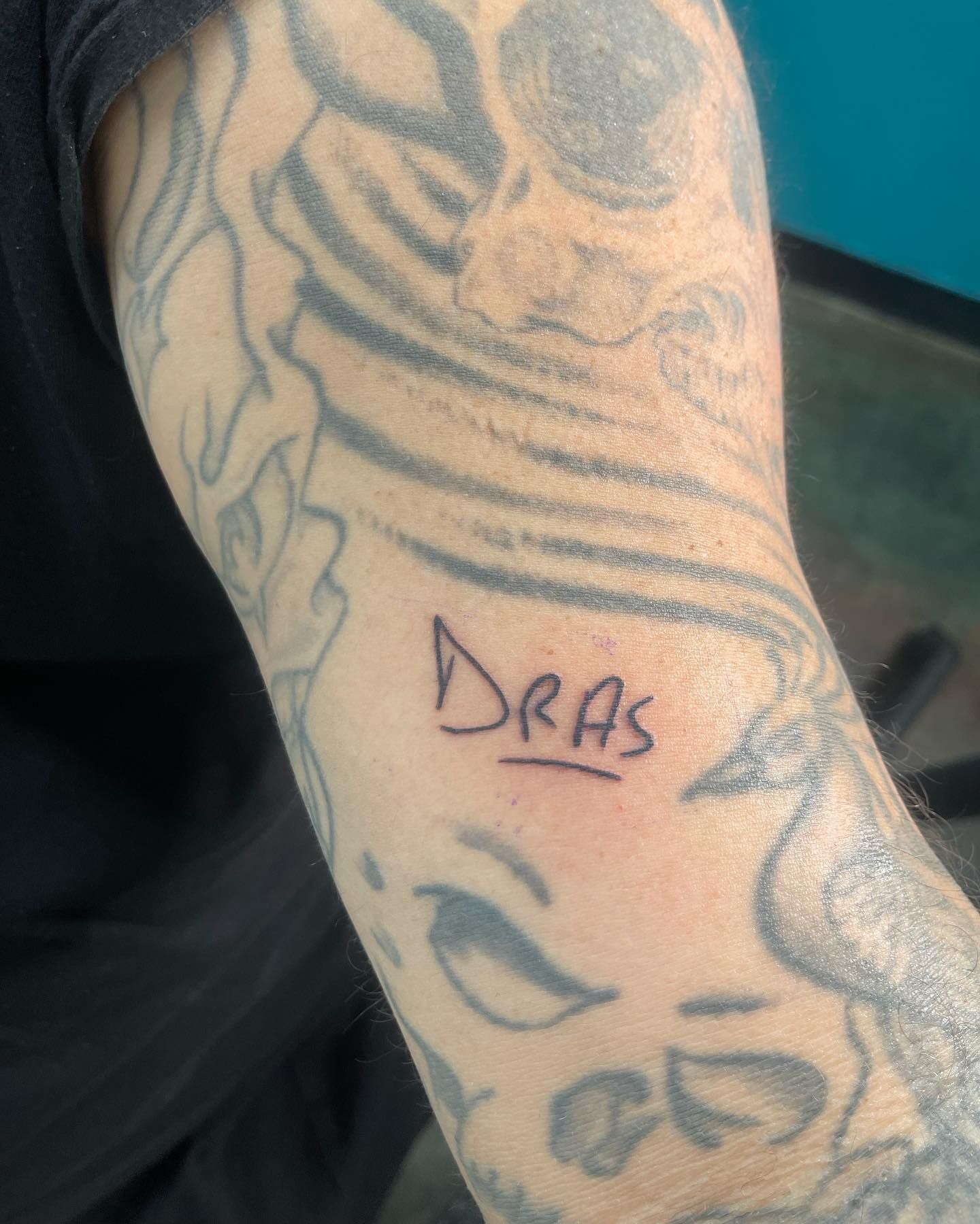 A person has a tattoo on their arm that says dras