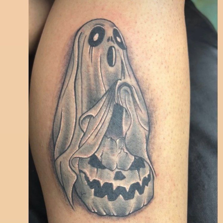 A tattoo of a ghost holding a pumpkin on a person 's leg