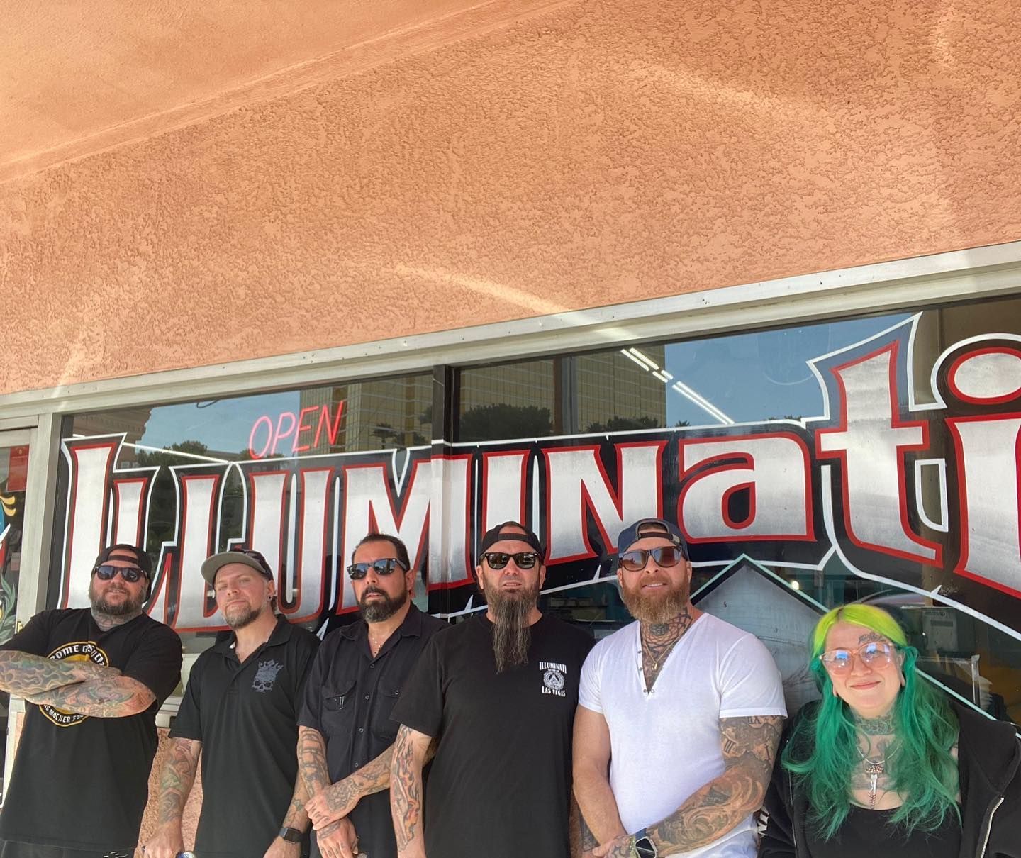 A group of people standing in front of a sign that says illuminati