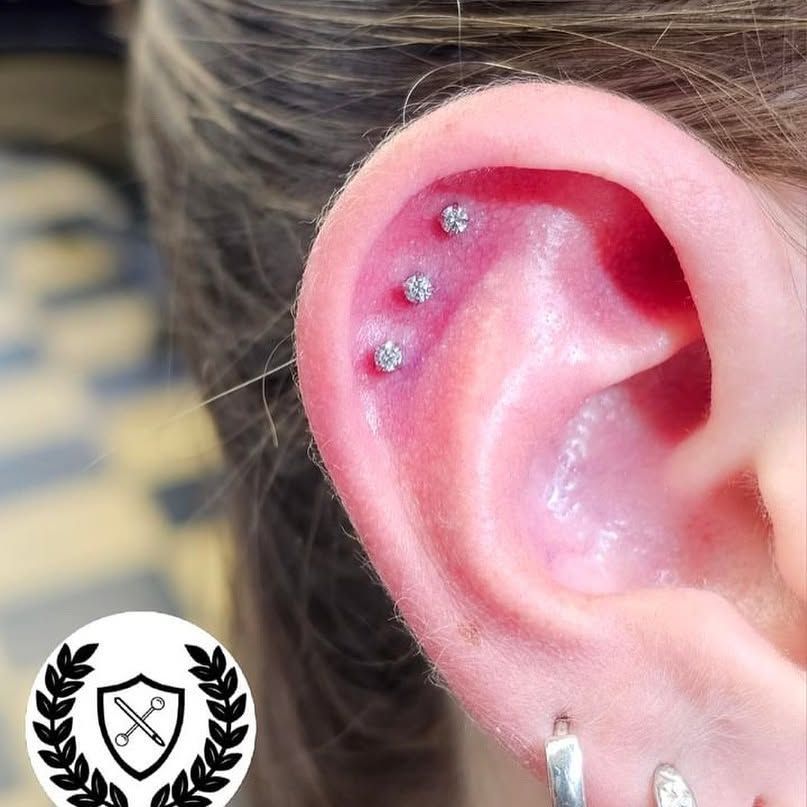 A close up of a woman 's ear with three piercings