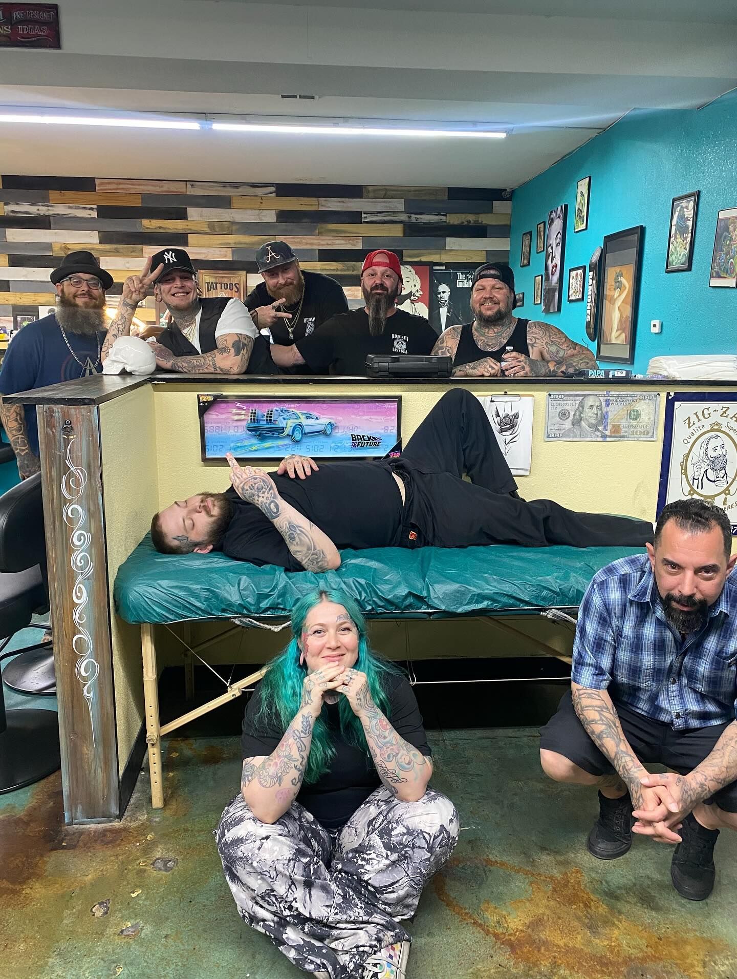 A group of people are posing for a picture in a tattoo shop.