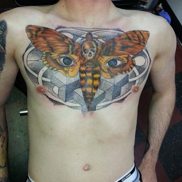 A man has a tattoo of a moth on his chest