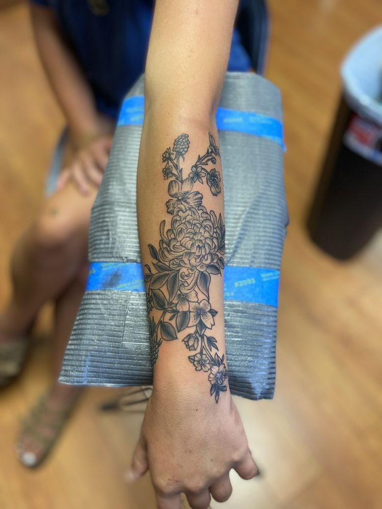 A woman has a tattoo of flowers on her arm