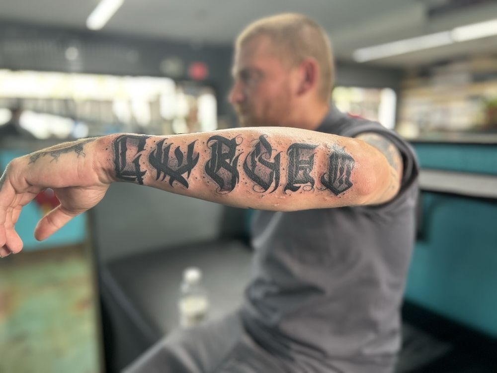 A man has a tattoo on his arm that says lwbgeg.