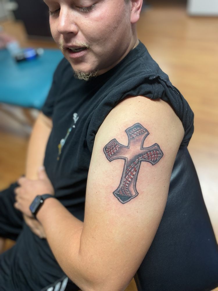 A man has a tattoo of a cross on his arm