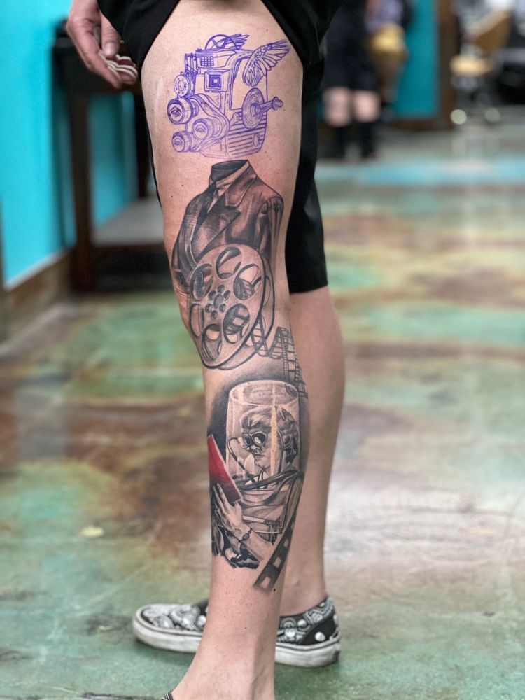 A person with a tattoo on their leg is standing in a room.