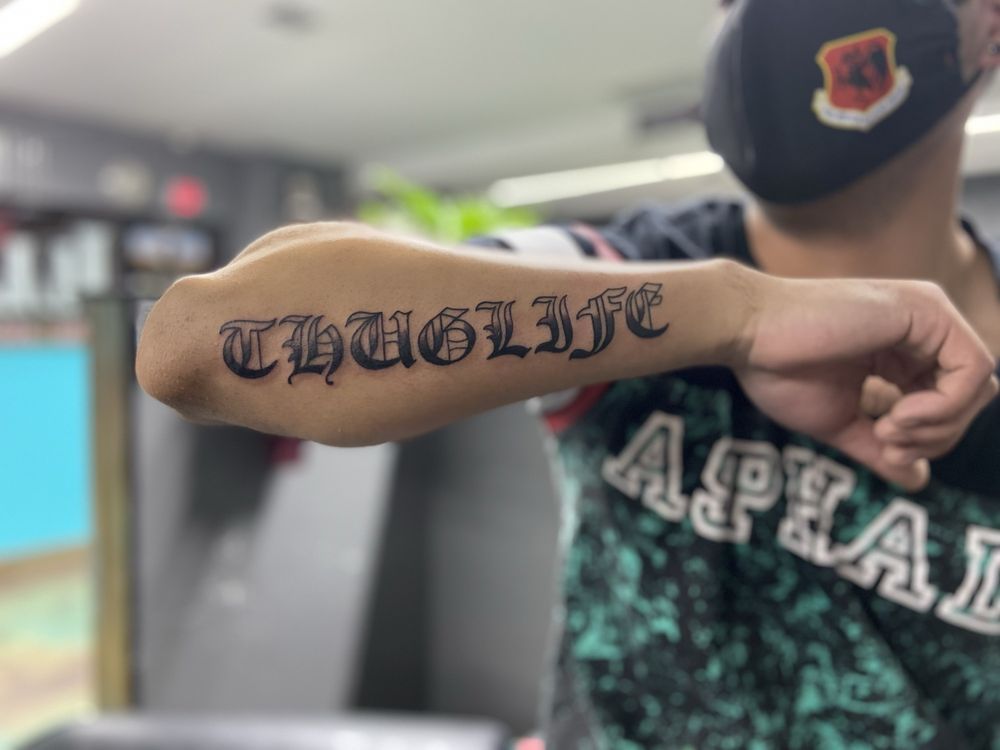 A man has a tattoo of the word thuglife on his arm