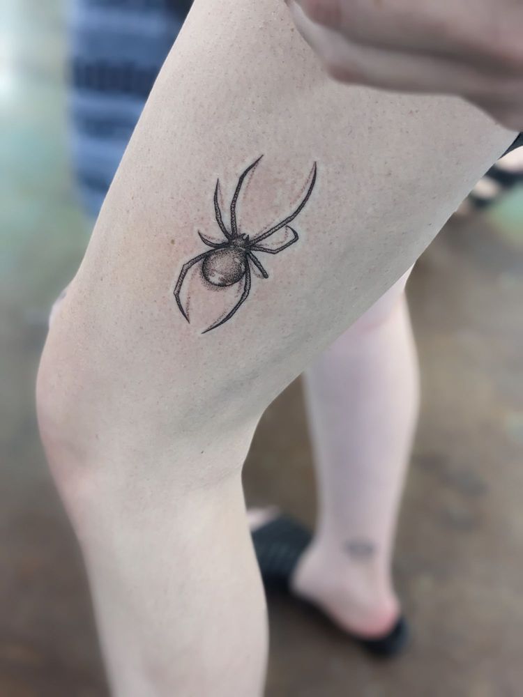 A person has a tattoo of a spider on their leg.