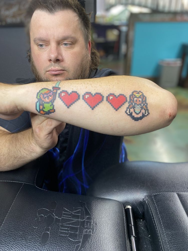 A man is sitting at a table with a tattoo on his arm.