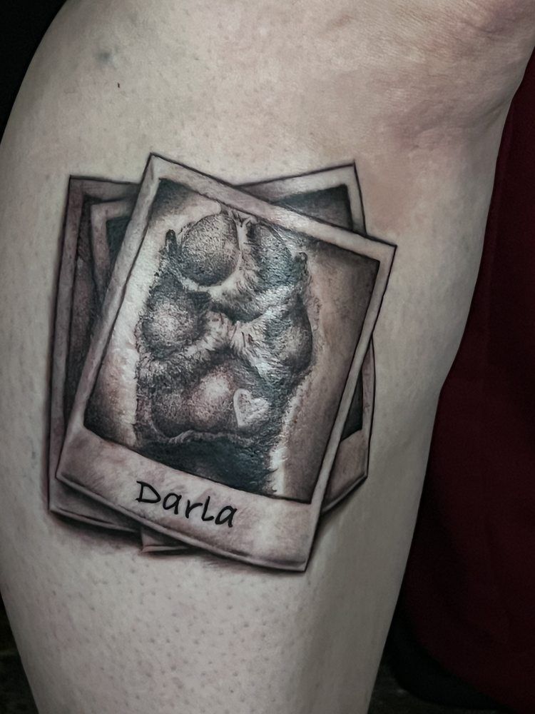 A person has a tattoo of a dog 's paw print on their leg.