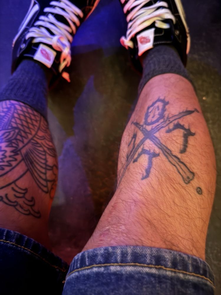 A person with a tattoo on their leg has a pair of nike shoes on