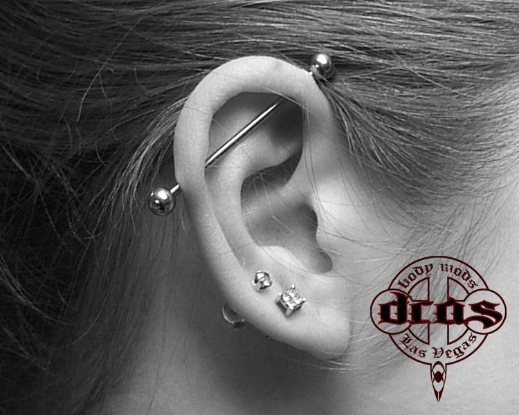 A black and white photo of a woman 's ear with multiple piercings
