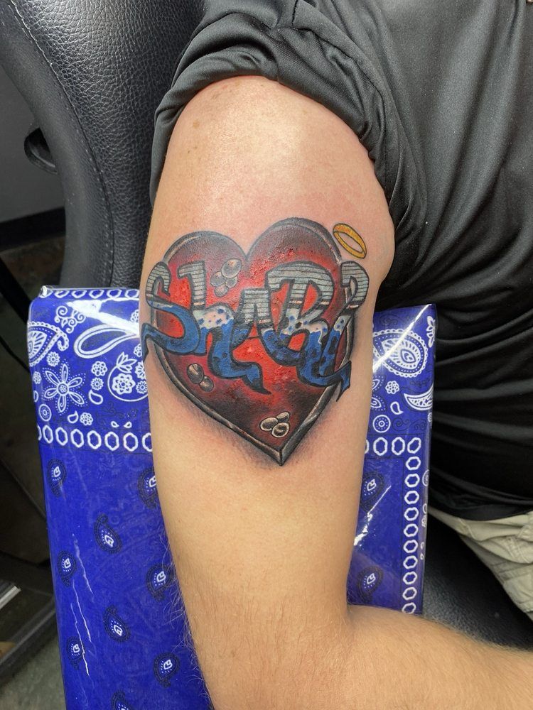 A man has a tattoo of a heart with the letters srb on it