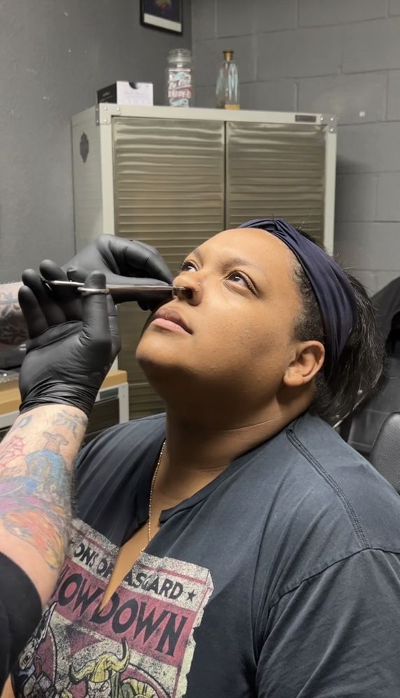 A woman is getting a tattoo on her nose.