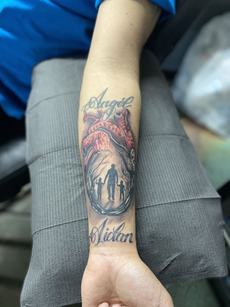 A person has a tattoo on their forearm that says angel