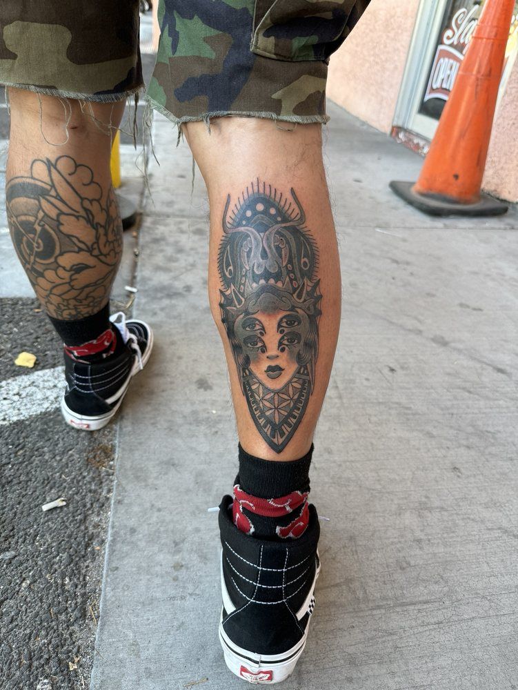 A person has a tattoo on their leg of a woman wearing a bandana.