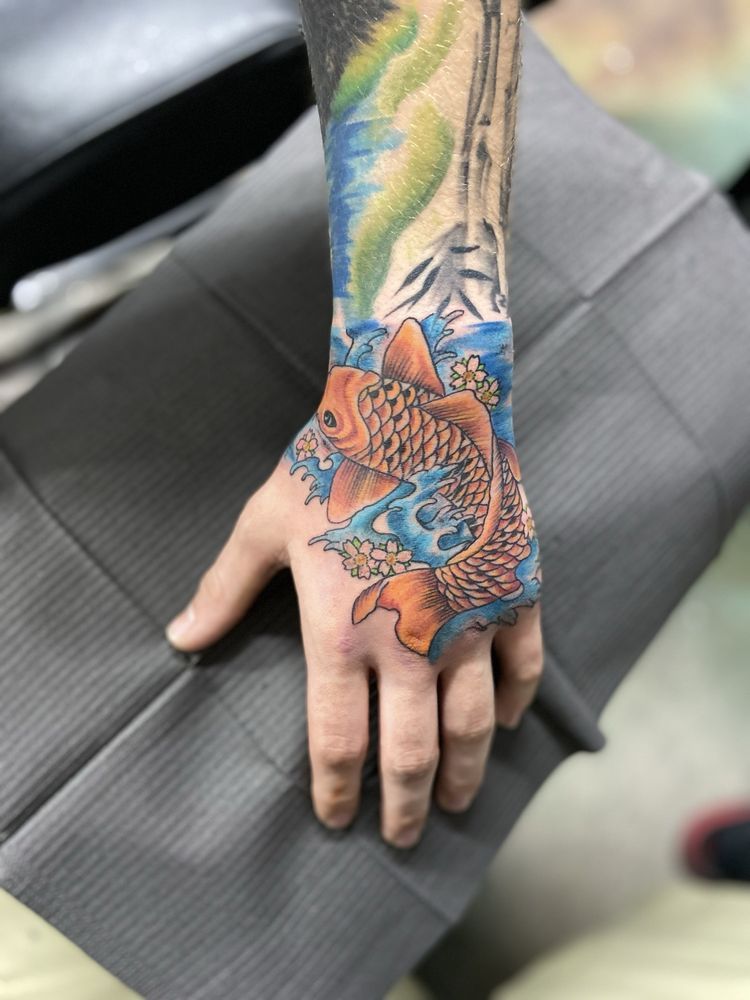 A person has a tattoo of a fish on their hand