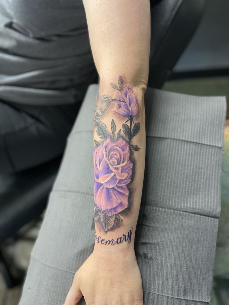 A woman has a tattoo of purple roses on her forearm.