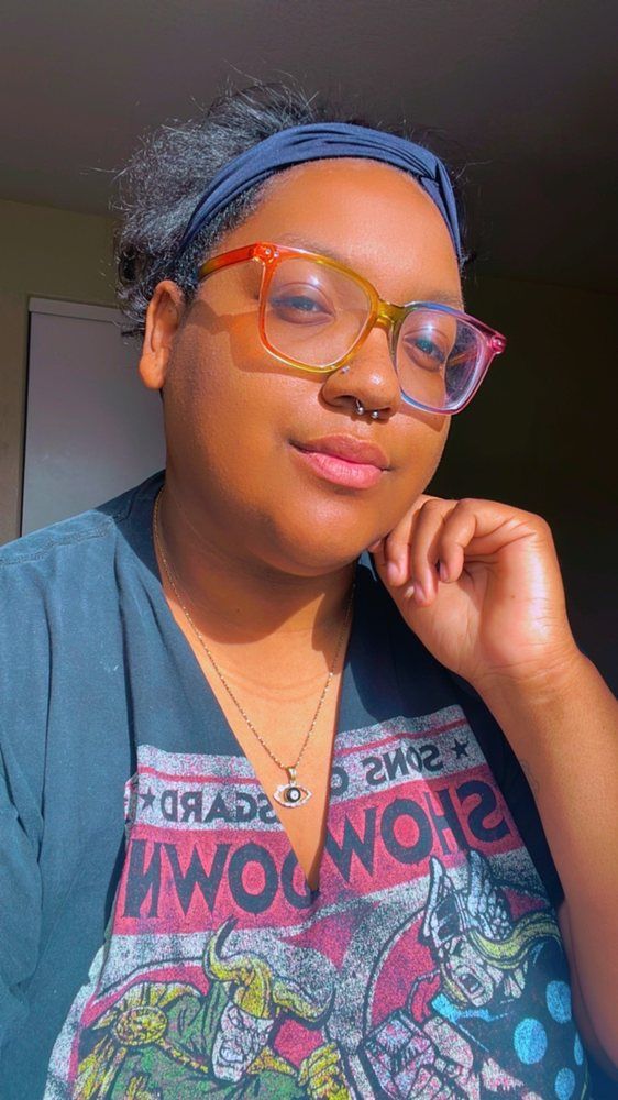 A woman wearing glasses and a headband is taking a selfie.