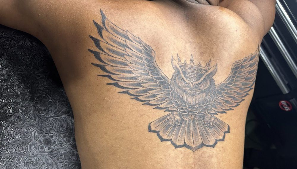 A man has a tattoo of an owl on his back.