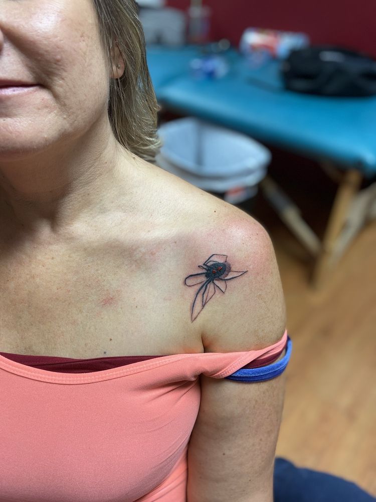 A woman has a tattoo of a flower on her shoulder.