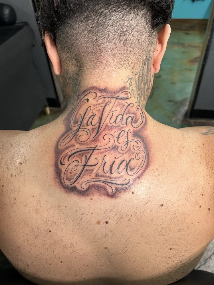 A man has a tattoo on his back that says `` la vida es fria ''.