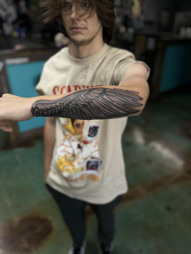 A man with a tattoo on his arm is wearing a coca cola shirt