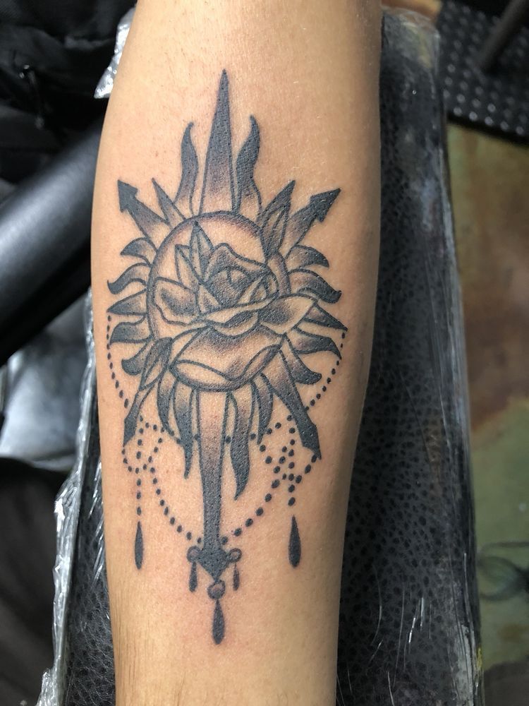 A black and white tattoo of a rose and a sun