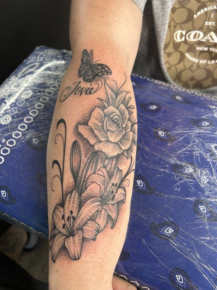 A person has a tattoo of flowers and a butterfly on their leg.