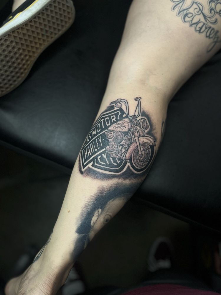 A person has a tattoo of a motorcycle engine on their leg