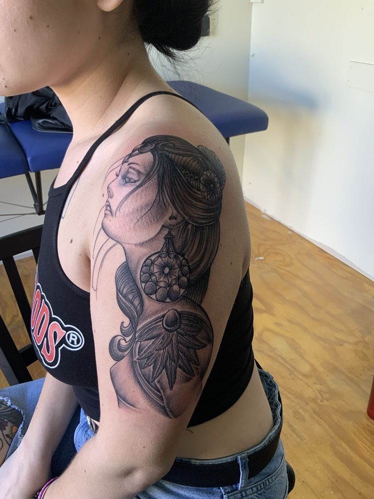 A woman has a tattoo of a woman 's face on her shoulder.